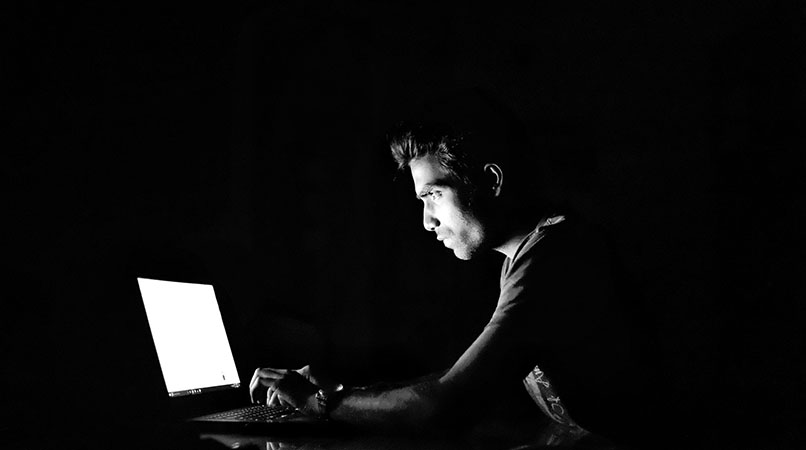 hombre usando laptop cuarto oscuro