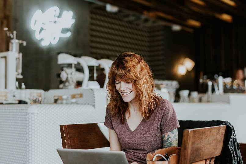 mujer utilizando una laptop en un cafe