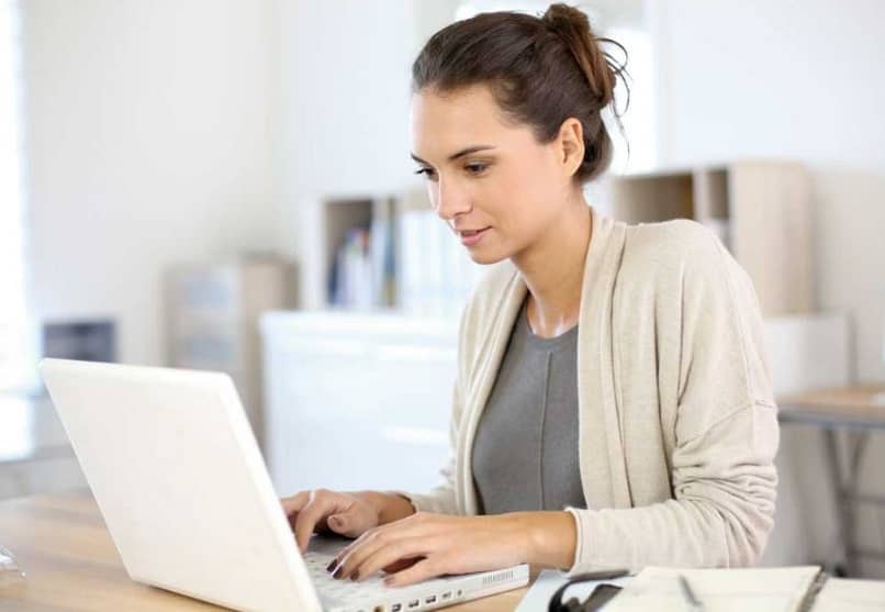 mujer en un escritorio utilizando una laptop 